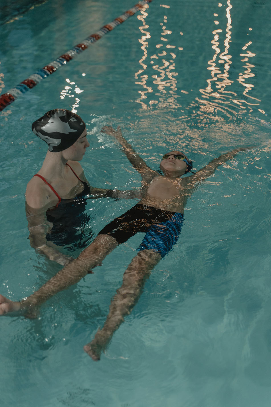 Instructor teaching child how to swim