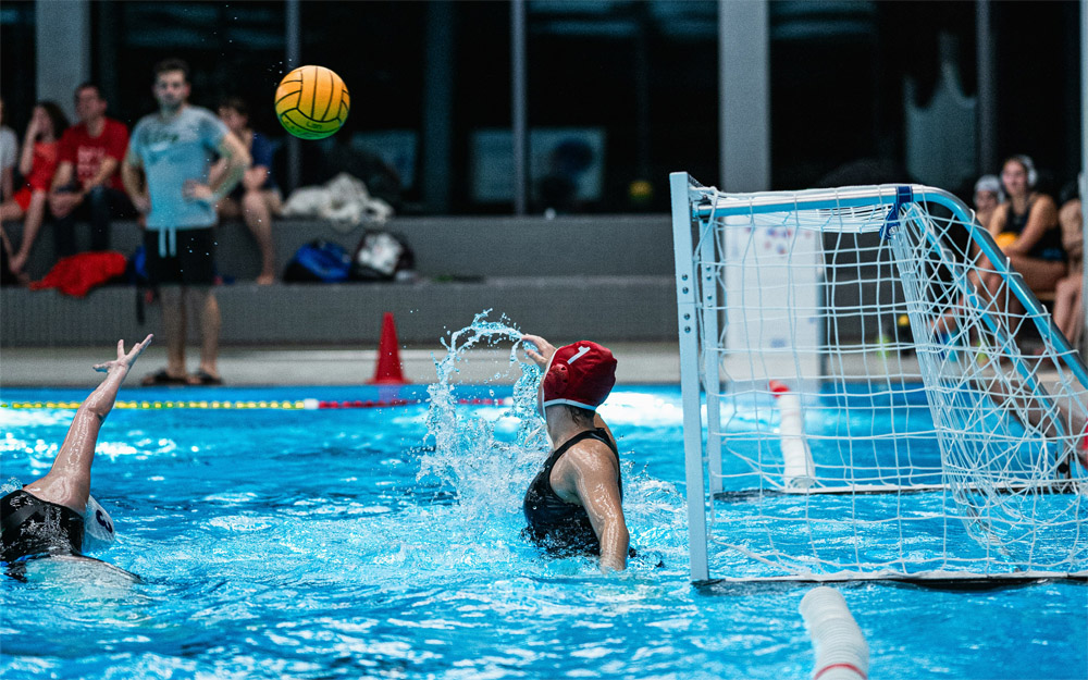 Women’s water polo goalie attempting to block a shot