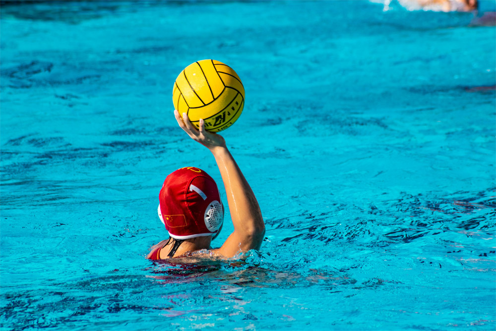 Women’s water polo player in pool with ball in hand